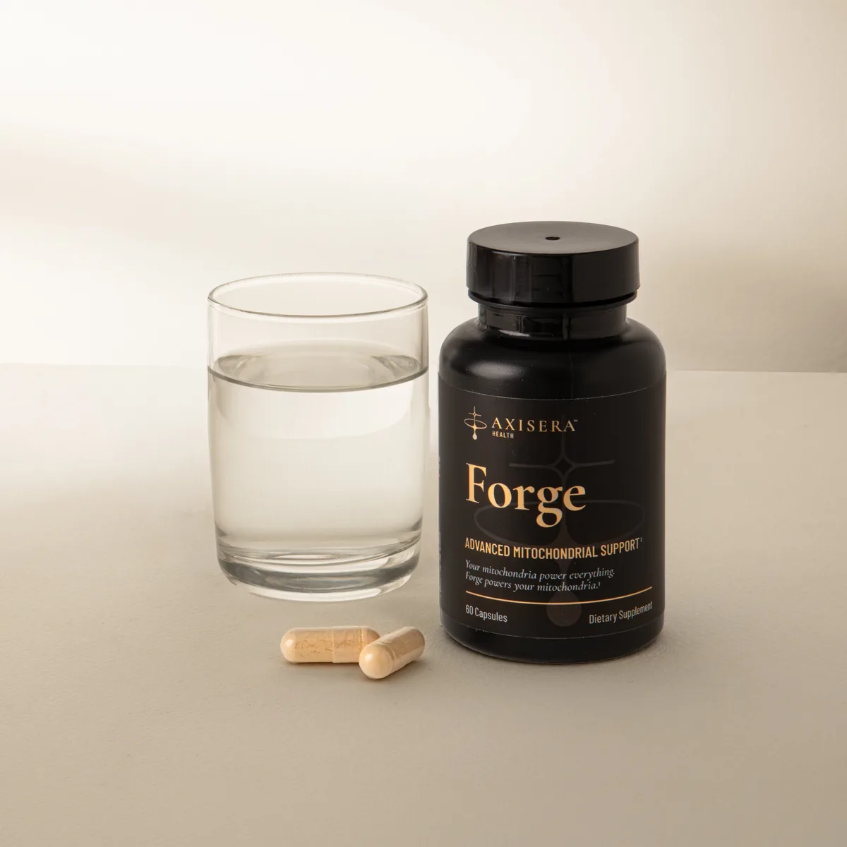 Axisera Forge bottle beside a glass of water and two capsules on a cream counter
